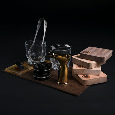 Luxury mixology gift set with cocktail glasses, gold torch, whiskey stones, wood shavings, and smoking boards by Helius Originals