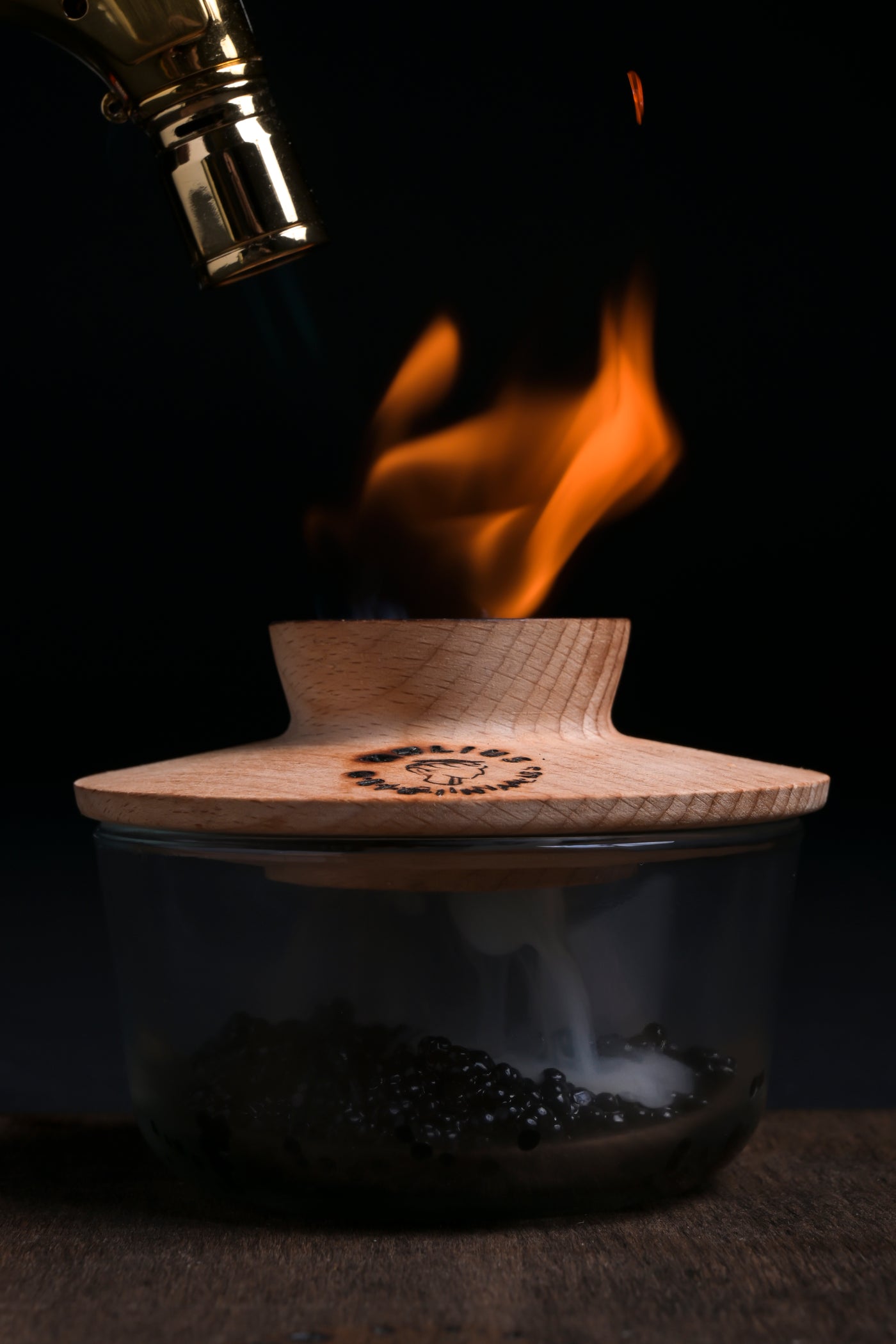 Luxury cocktail smoker torch infusing caviar with fire and aromatic smoke using the Helius Originals smoking saucer.