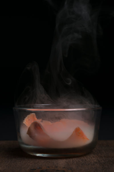Glass bowl of smoked salmon infused with reclaimed Ontario wood shavings using the Helius Originals cocktail smoker, eco-luxury mixology and barware