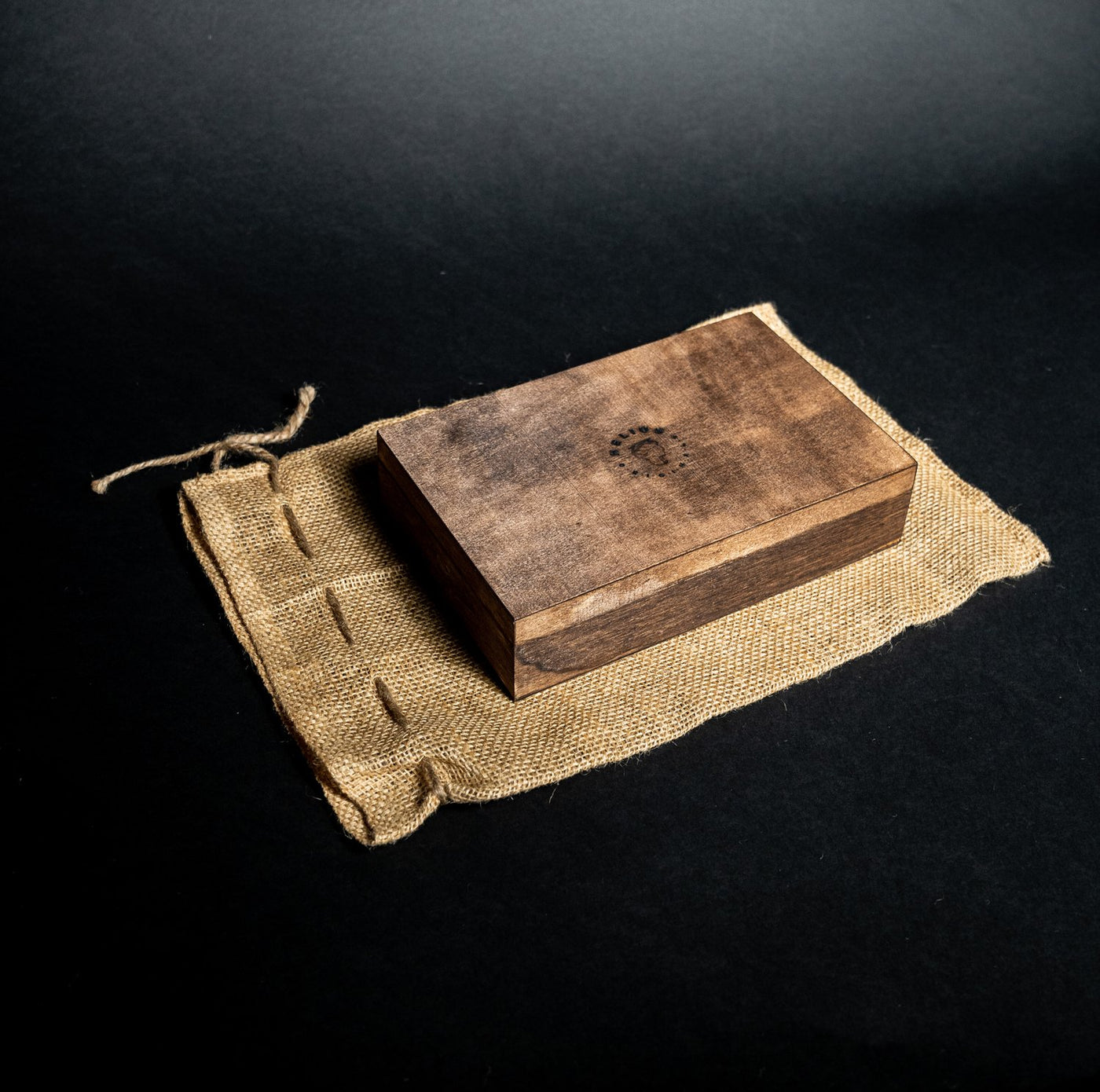 Helius Originals wooden gift box, presented on a rustic burlap bag for sustainable luxury packaging.